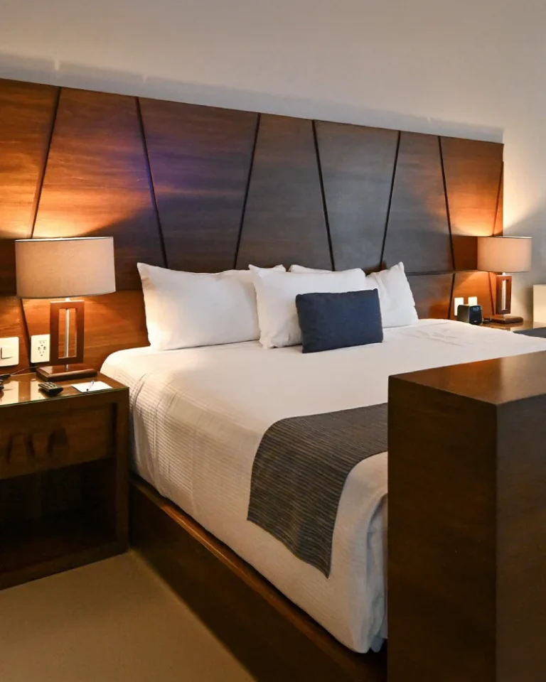 Habitación de hotel moderna con cama grande, iluminación cálida y decoración elegante.